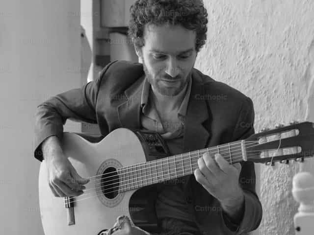 Jove tocando la guitarra. Foto en blanco y negro - Banco de imágenes católicas