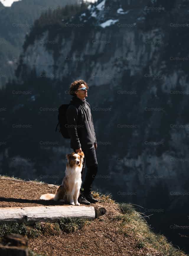 Jeune homme avec son animal de compagnie dans les montagnes - Images catholiques de stock