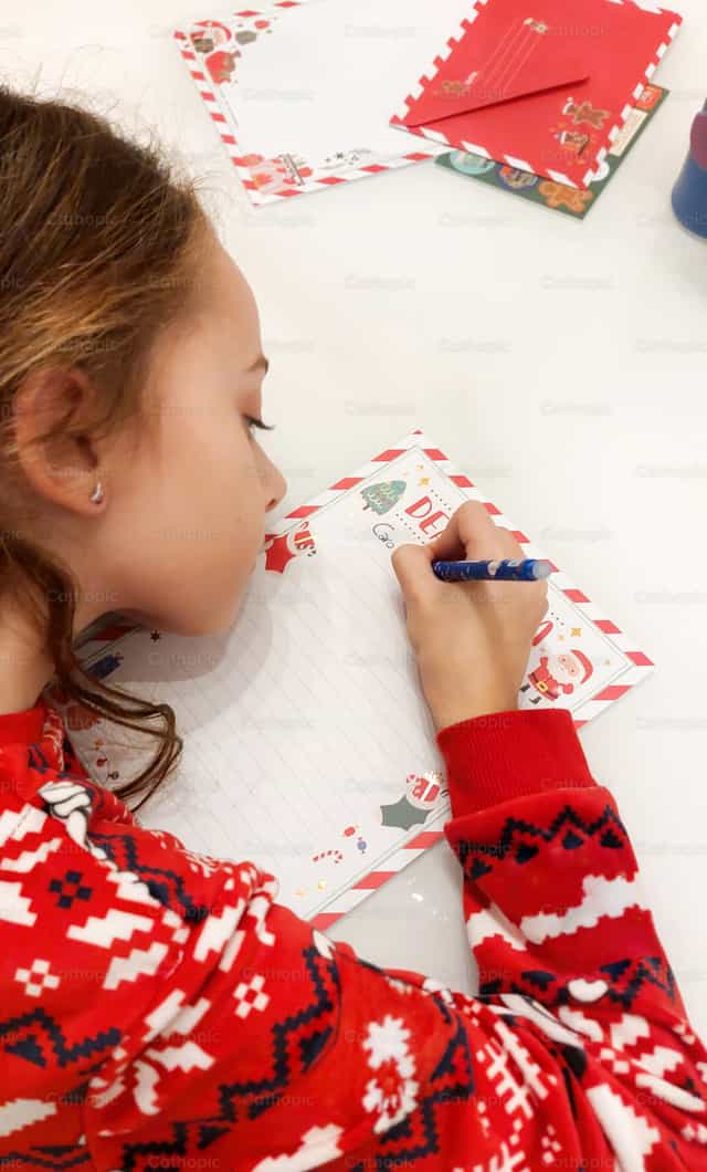 Enfant écrivant une lettre de liste de souhaits de Noël au Père Noël - Images catholiques de stock