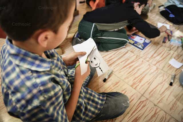Niño recortando su dibujo - Banco de imágenes católicas