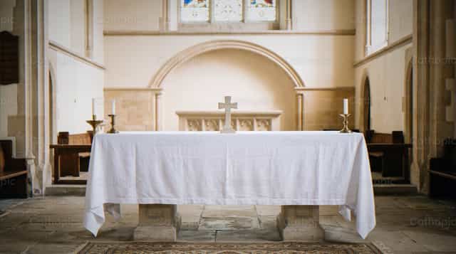 Altare drappeggiato con croce nel santuario della chiesa - Immagini stock cattoliche