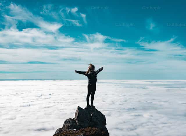 Mujer abre sus manos en la cima de la montaña - Banco de imágenes católicas - Fotografía por Santiago de la Hoz