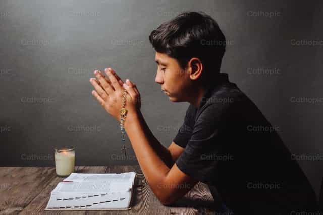 Joven orando con la Biblia y Rosario - Banco de imágenes católicas - Fotografía por Gerardo Juarez