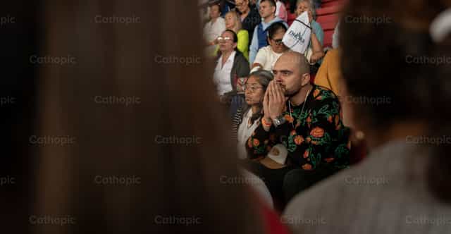 Homem em oração entre a comunidade - Imagens católicas de stock