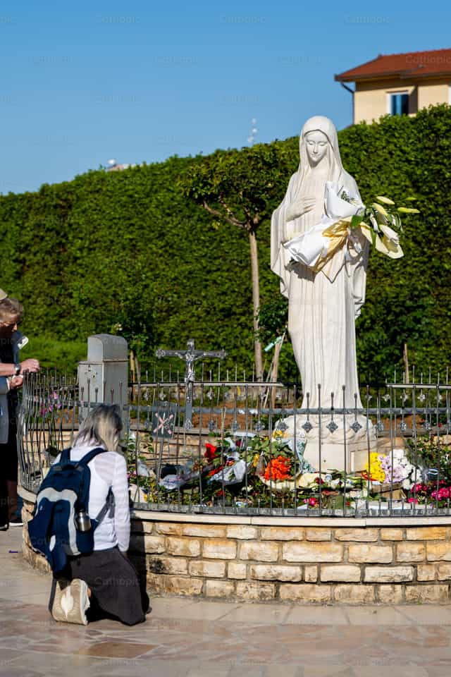 Prayer before Statue of Virgin Mary in Medjugorje - Catholic stock images - Photo by Metod Perme