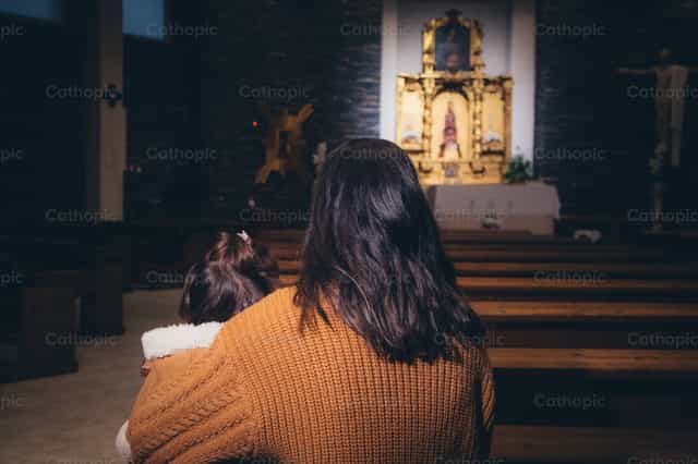 Madre e hija rezando ante el altar - Banco de imágenes católicas - Fotografía por Almures Studio