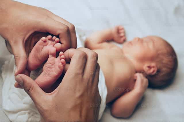Bebé recién nacido (manos de los padres) - Banco de imágenes católicas - Fotografía por Clina CG