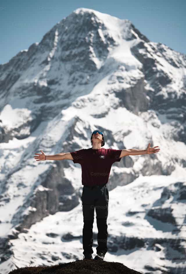 Hombre con las manos abiertas en la cima de una montaña - Banco de imágenes católicas - Fotografía por Santiago de la Hoz