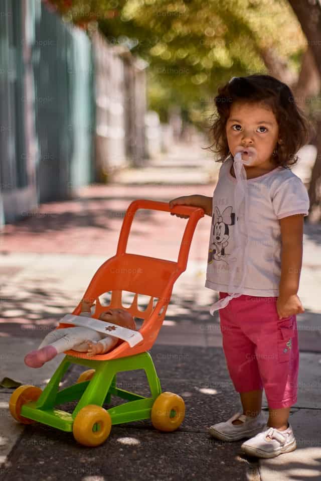 Menina pequena com brinquedo - Imagens católicas de stock - Foto de Pitangus Alfonso Asensio