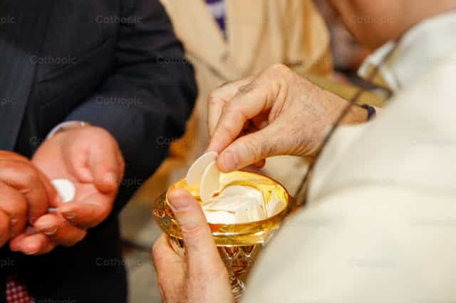 Pari na may hawak na kalis na may mga konsekraadong hostya - Mga Catholic stock image - Larawan ni Antonio Gravante