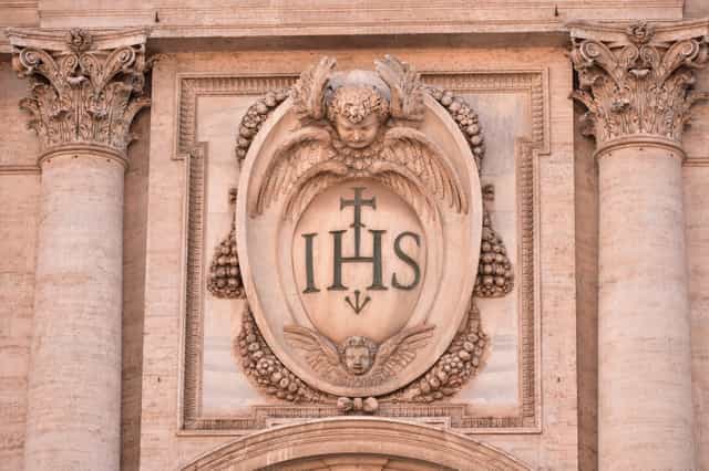 Inscripción IHS en la fachada exterior de la Chiesa del Gesù, Roma. - Banco de imágenes católicas