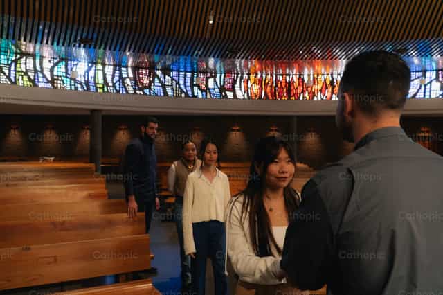 Jovens e sacerdote em encontro multicultural - Imagens católicas de stock
