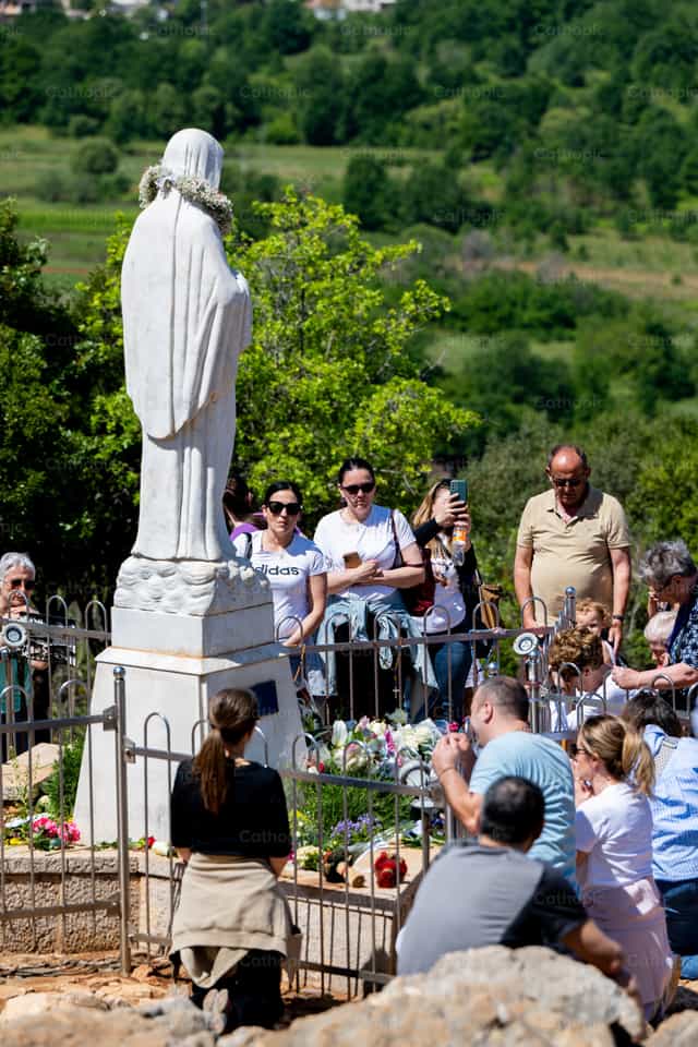 A group of faithful pray before the statue of Mary - Catholic stock images - Photo by Metod Perme