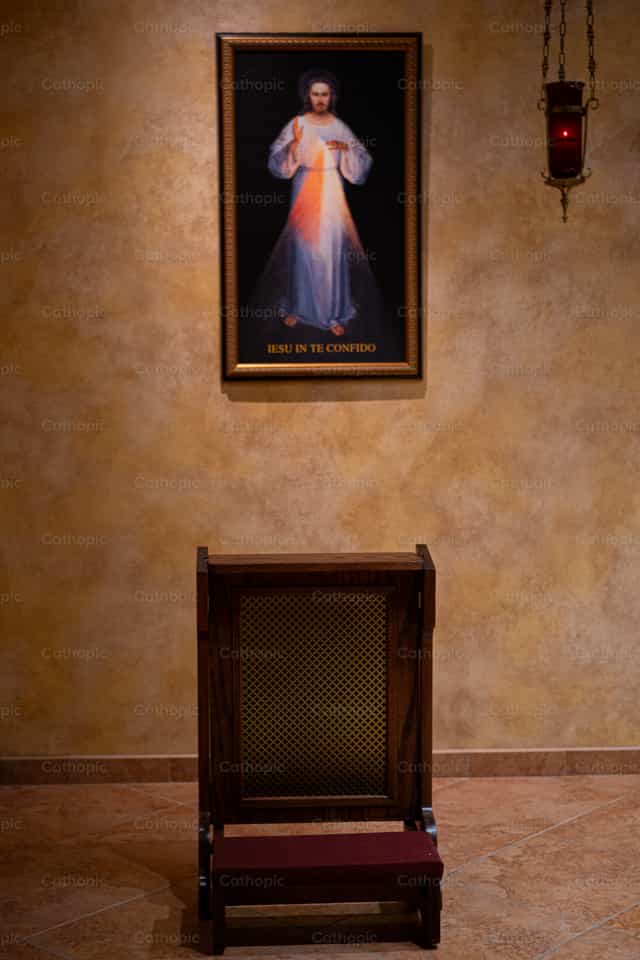 Ginocchiatoio davanti all’immagine della Divina Misericordia - Immagini stock cattoliche